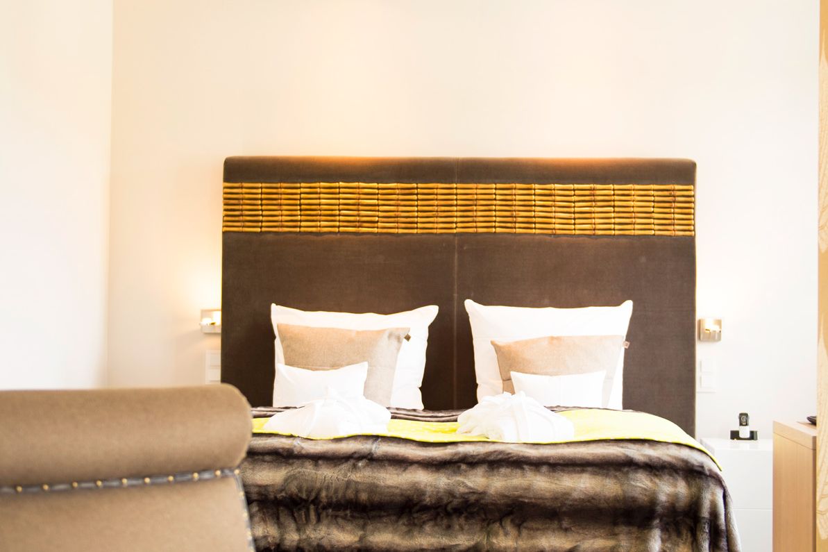 Großes Doppelbett und Sessel im Hotelzimmer Refugiumsuite im Hotel Hof Galerie