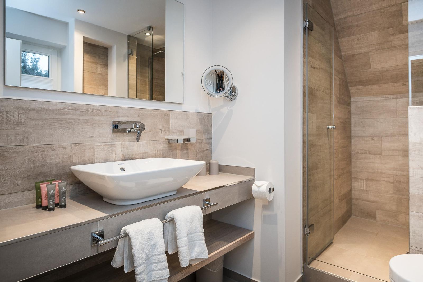 Badezimmer mit Waschbecken und ebenerdiger Dusche im Hotel Landhaus Sylter Hahn in Westerland auf Sylt