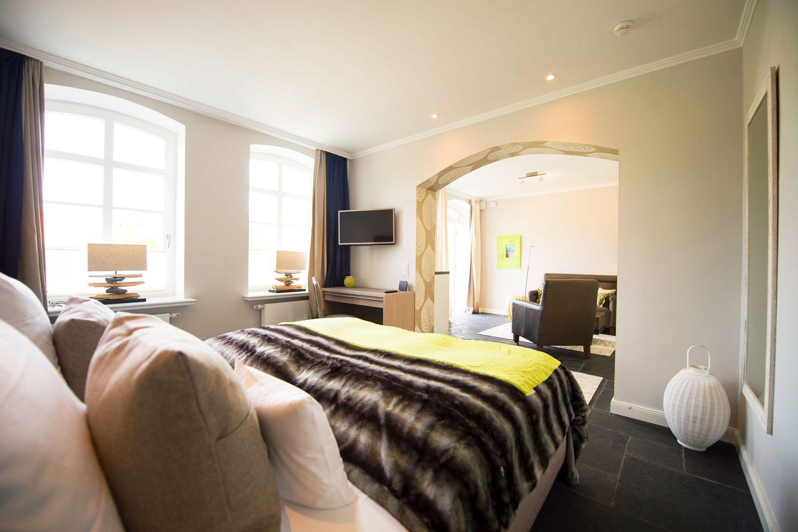 Schlafzimmer mit Doppelbett, Fernseher und Zugang zum Wohnzimmer in der Refugiumsuite im Hotel Hof Galerie