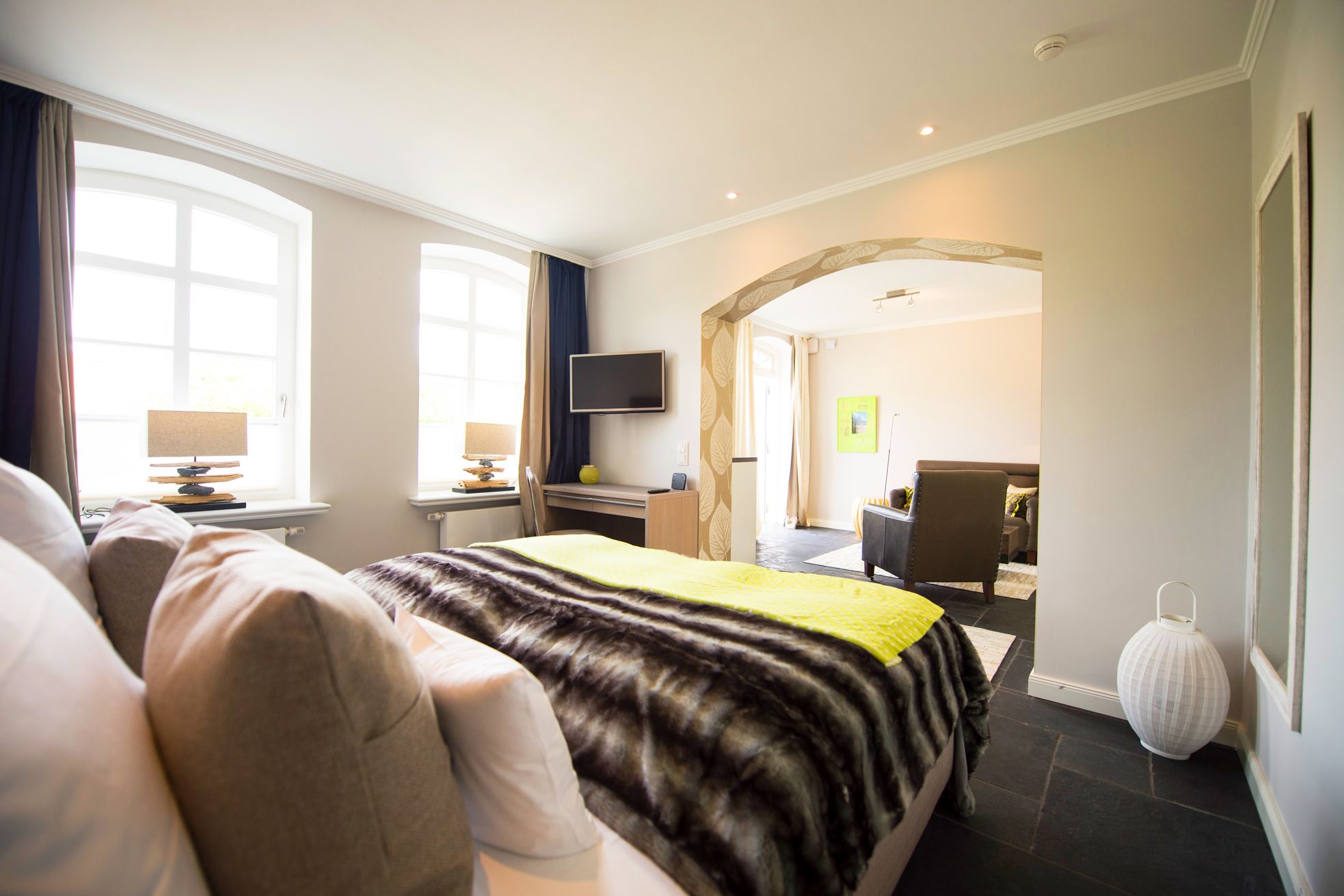 Schlafzimmer mit Doppelbett, Fernseher und Zugang zum Wohnzimmer in der Refugiumsuite im Hotel Hof Galerie