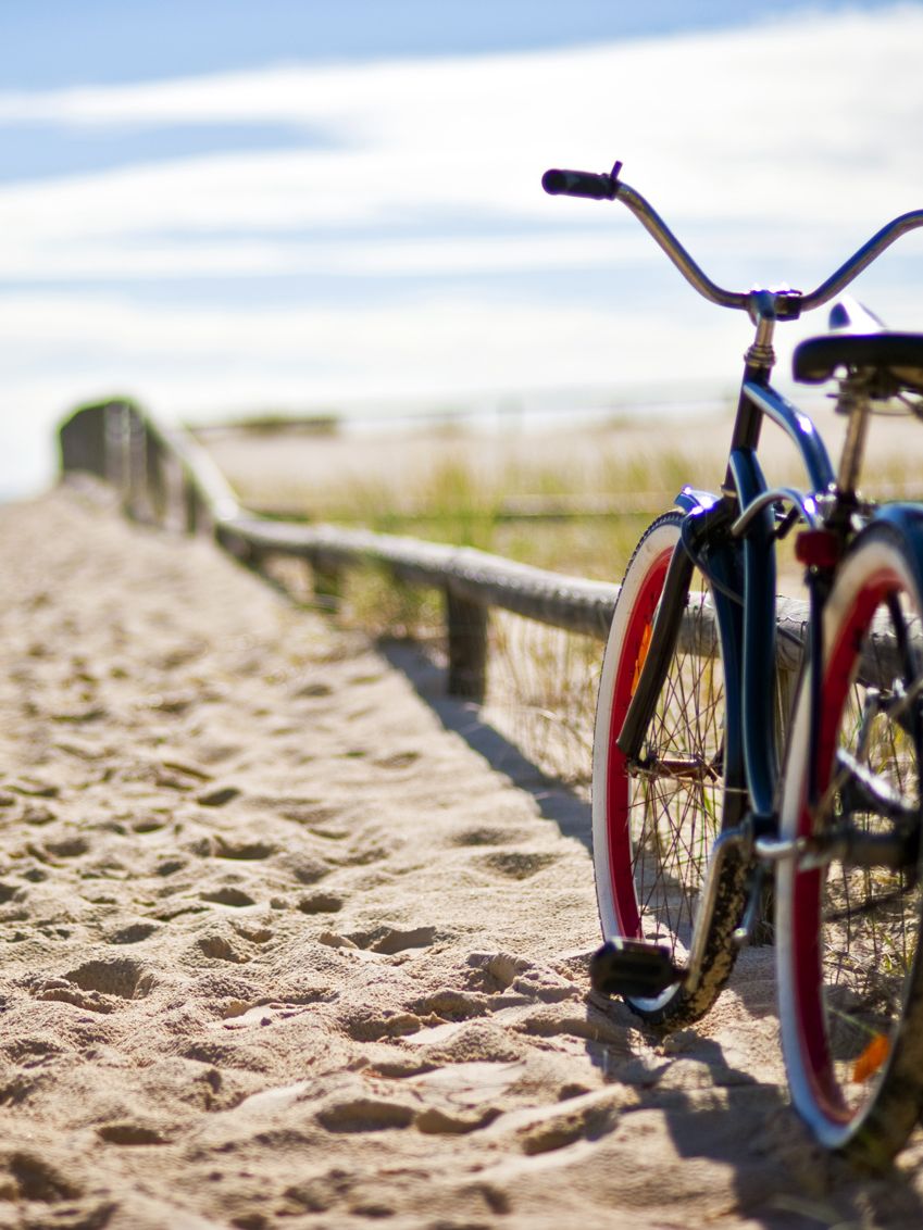 Foto zeigt ein Fahrrad angelehnt am Zaun eines Strandüberganges