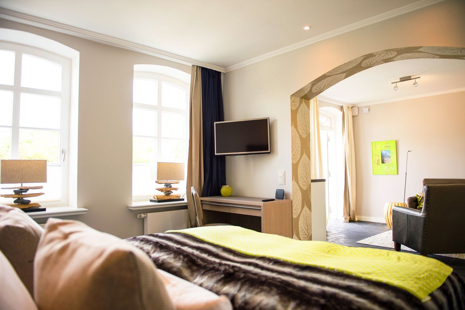 Refugiumsuite mit Doppelbett, Fernseher und Wohnzimmer im Hotel Hof Galerie in Morsum auf Sylt